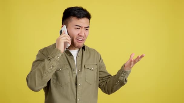 Angry Chinese Man Talking Mobile Studio Yellow Background — Stock Video