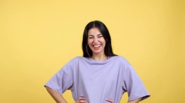 Happy hispanic woman laughing and looking at the camera in studio with yellow background