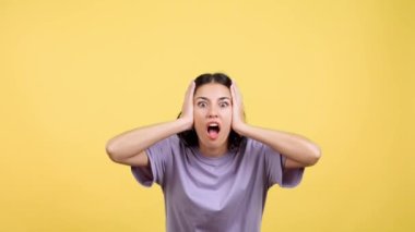 Surprised hispanic woman gesturing and looking at the camera in studio with yellow background