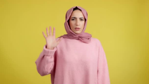 黄色の背景を持つスタジオで手で禁止をジェスチャーイスラム教徒女性 — ストック動画
