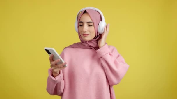 Mujer Musulmana Feliz Sonriendo Mientras Escucha Música Con Móvil Auriculares — Vídeo de stock