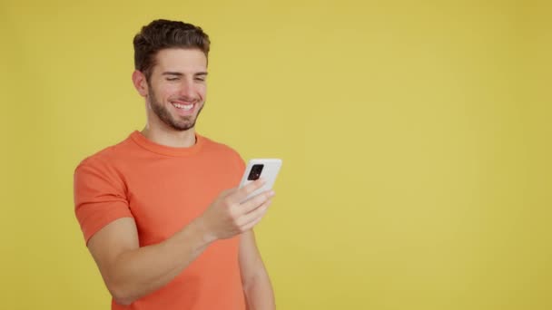 Happy Caucasian Man Smiling While Using Mobile Studio Yellow Background — Stockvideo