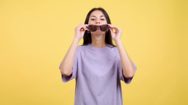 Rude Hispánská Žena Slunečními Brýlemi Při Pohledu Kameru Studiu Žlutým — Stock video