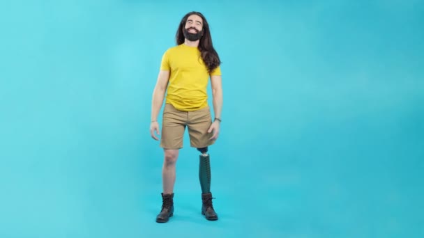 スタジオビデオともに青の背景とコピースペースの幸せな男で脚の義肢のある有名人で祝う空中 — ストック動画