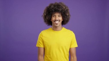 Happy cool african man with curly hair looking at camera with arms crossed in studio