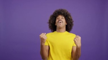 Happy african man looking at the camera and celebrating raising the fists in studio