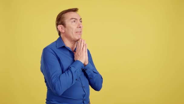 Ώριμος Άνθρωπος Προσεύχεται Διπλωμένα Χέρια Στο Στούντιο Κίτρινο Φόντο — Αρχείο Βίντεο