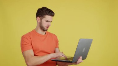 Caucasian man having a problem with a laptop in studio with yellow background