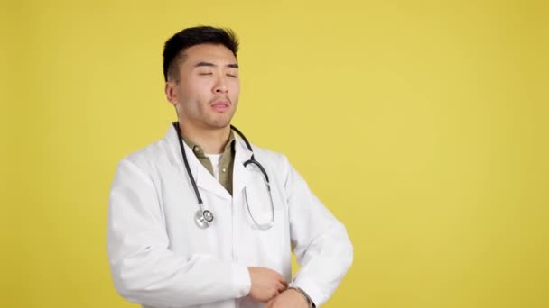 Serious Chinese Doctor Arms Crossed Looking Away Studio Yellow Background — Stockvideo