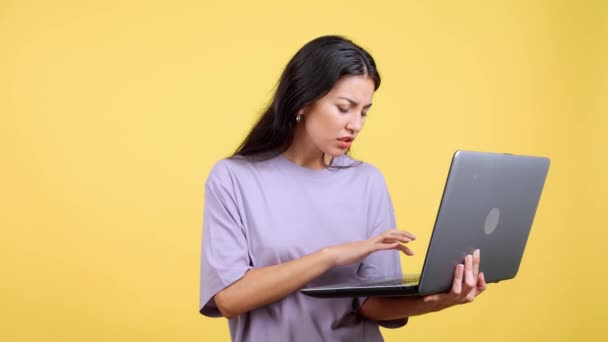 有问题的高加索女人在工作室里有一个黄色背景的笔记本电脑 — 图库视频影像