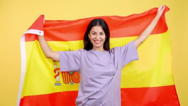 幸せな白人女性笑顔と黄色の背景とスタジオでスペイン国旗を上げます — ストック動画