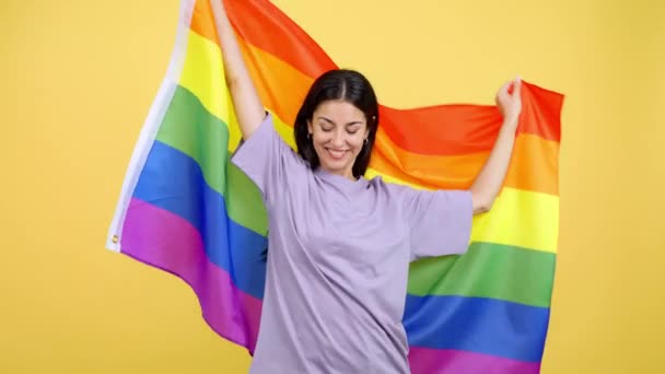 快乐的高加索女人在有黄色背景的演播室里升起了一磅彩虹旗 — 图库视频影像