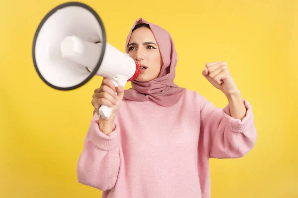 黄色の背景を持つスタジオで怒りでスピーカーを使用して動揺イスラム教徒の女性 — ストック写真
