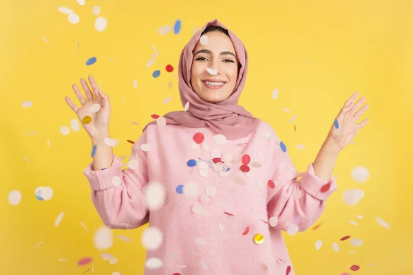 Happy Muslim Woman Surrounded Confetti Flying Air Studio Yellow Background — Stock Photo, Image