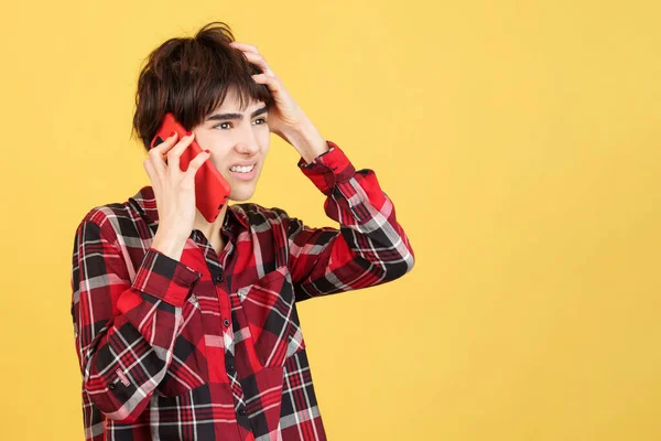 Furious androgynous person talking to the mobile in studio with yellow background