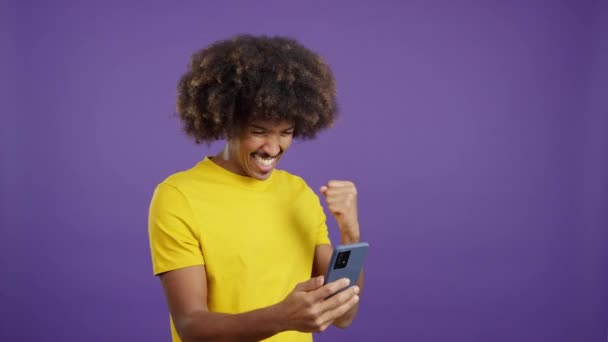 Возбужденный Африканский Мужчина Вьющимися Волосами Празднует Время Использования Мобильного Телефона — стоковое видео