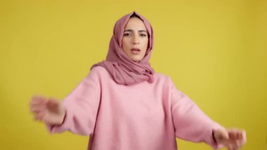 Kaba Müslüman kız, kameraya bakarak boks yapıyor. Sarı arkaplan