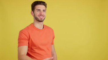 Stüdyoda sarı arka planda bir hediye alırken gülümseyen mutlu beyaz adam.