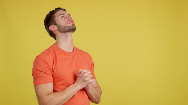白人男見上げながら祈りますともに折り畳まれた手でスタジオとともに黄色の背景 — ストック動画