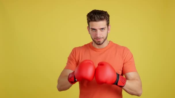 コーカシア人男とともに赤ボクシング手袋で戦いポーズでスタジオでともに黄色の背景 — ストック動画
