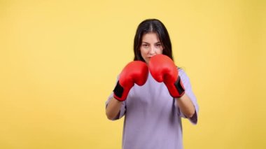 Caucasian woman with boxing gloves in fight pose with yellow background