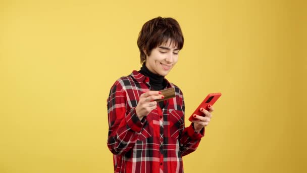 Androgynous Sarı Arka Planlı Cep Telefonuyla Online Alışveriş Yapıyor — Stok video