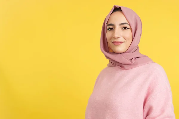 幸せなイスラム教徒の女性身に着けていますヒジャーブ見ますザ カメラでスタジオで黄色の背景 — ストック写真