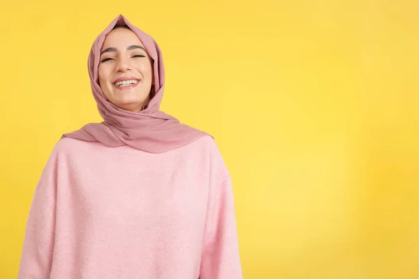 美人若いですムスリム女性身に着けていますHijab笑顔でスタジオとともに黄色の背景 — ストック写真