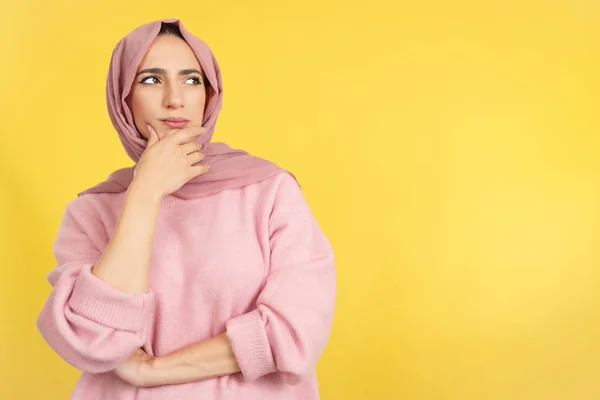 顔に手でイスラム教徒の女性と黄色の背景を持つスタジオで思慮深い表現 — ストック写真