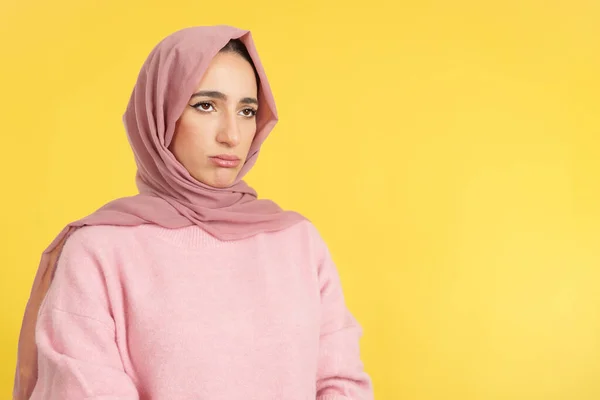 悲しいですイスラム教徒女性身に着けています頭スカーフ見ます離れてスタジオでともに黄色の背景 — ストック写真