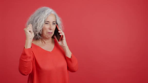 Studio Video Červeným Pozadím Dospělé Ženy Slaví Při Rozhovoru Mobilním — Stock video