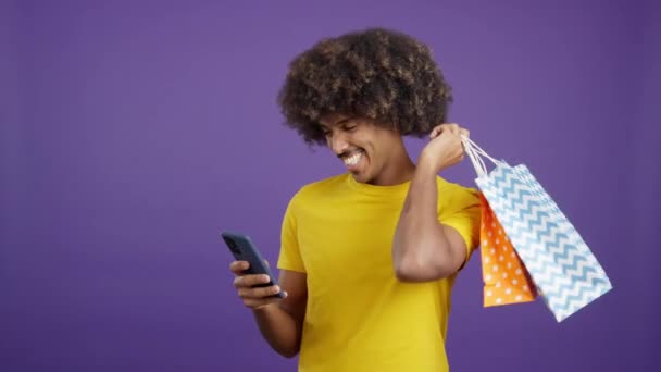Smiley African Man Curly Hair Using Mobile While Holing Shopping — Αρχείο Βίντεο