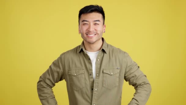 Mutlu Çinli Adam Sarı Arka Planlı Bir Stüdyoda Parmak Kaldırıyor — Stok video