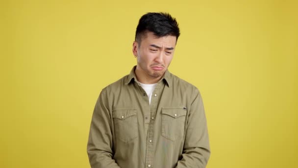 Smutný Pohledný Číňan Při Pohledu Kameru Studiu Žlutým Pozadím — Stock video