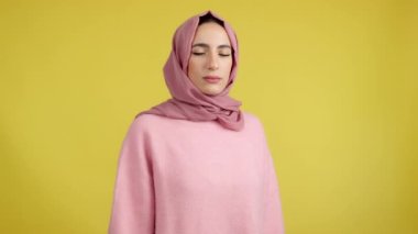 Muslim woman gesturing with the hands in fear in studio with yellow background