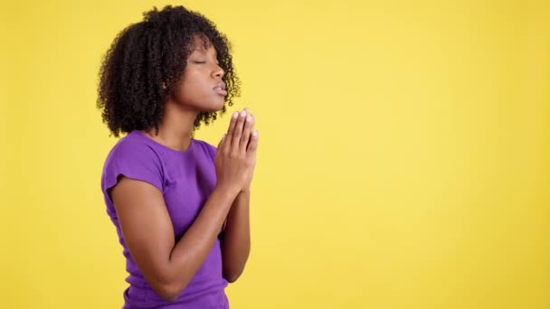 Афро Женщина Молится Глядя Вверх Взявшись Руки Студии Желтым Фоном — стоковое видео