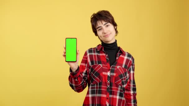 Androgynous Sarı Arkaplan Ile Yeşil Mobil Ekrana Bakıyor — Stok video