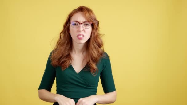Κοκκινομάλλα Γυναίκα Γυαλιά Κοιτάζοντας Την Κάμερα Δυσπιστία Στο Στούντιο Κίτρινο — Αρχείο Βίντεο