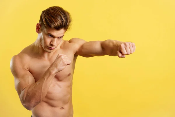 強いです男ありますシャドウボクシングとともに裸胴でスタジオで黄色の背景 — ストック写真