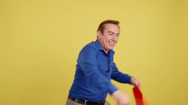 Счастливый Зрелый Мужчина Поднимает Радужный Флаг Студии Жёлтым Фоном — стоковое видео