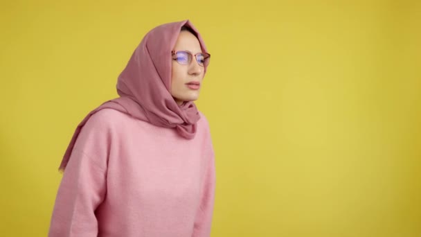 Мусульманская Женщина Снимает Очки Глядя Сторону Студии Желтым Фоном — стоковое видео