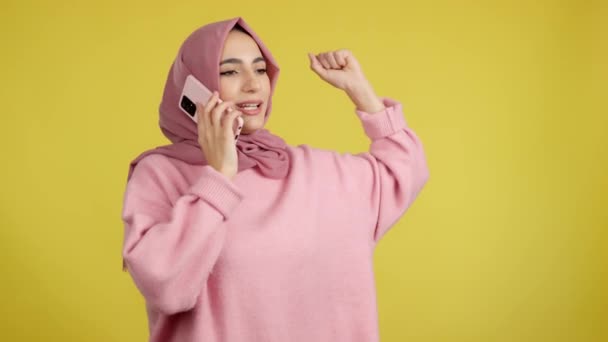 Happy Muslim Woman Celebrating While Talking Mobile Phone Studio Yellow — ストック動画