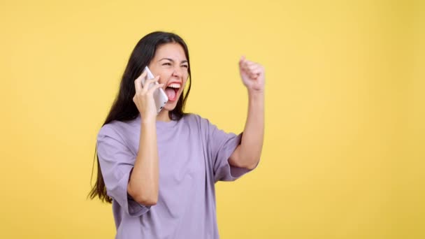 快乐的女人带着黄色背景的手机去工作室庆祝 — 图库视频影像