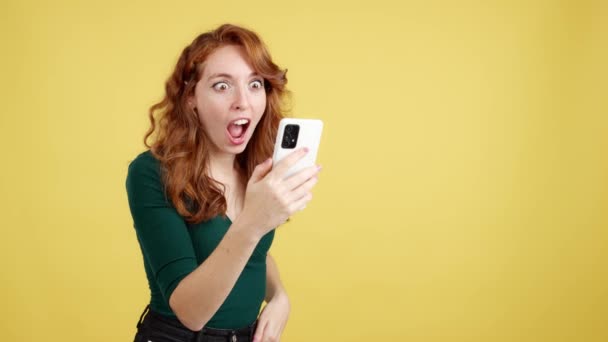 Verrast Roodharige Vrouw Zoek Naar Het Scherm Van Een Mobiele — Stockvideo