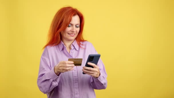 Ευτυχισμένη Ώριμη Κοκκινομάλλα Γυναίκα Που Χρησιμοποιεί Κινητό Και Την Κάρτα — Αρχείο Βίντεο