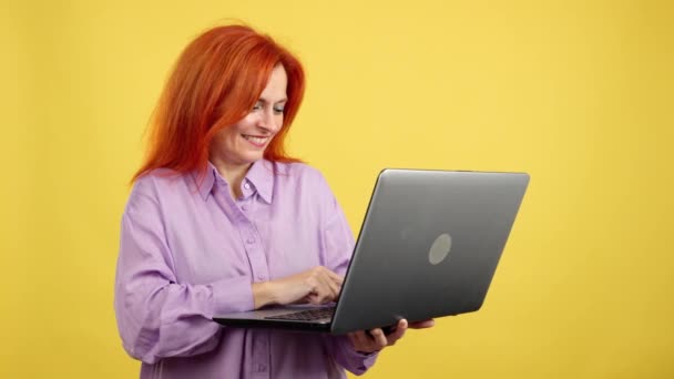 Roodharige Volwassen Vrouw Glimlachen Terwijl Met Behulp Van Een Laptop — Stockvideo