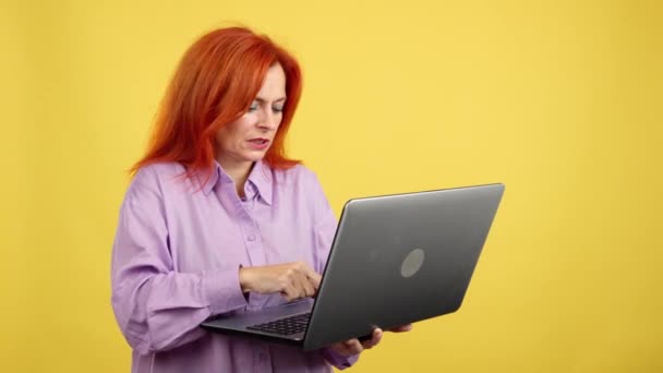 Зрелая Рыжая Женщина Имеющая Проблемы Ноутбуком Студии Желтым Фоном — стоковое видео