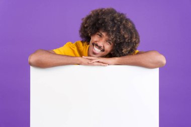 Stüdyoda boş bir panele yaslanan kıvırcık saçlı havalı Afrikalı adam.