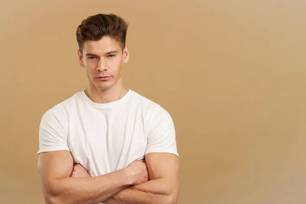 stock image Proud strong man looking at camera with arms folded in studio with brown background