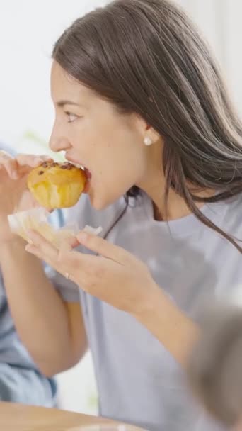 一个惊慌失措的女人在家吃纸杯蛋糕的垂直慢镜头简介 — 图库视频影像